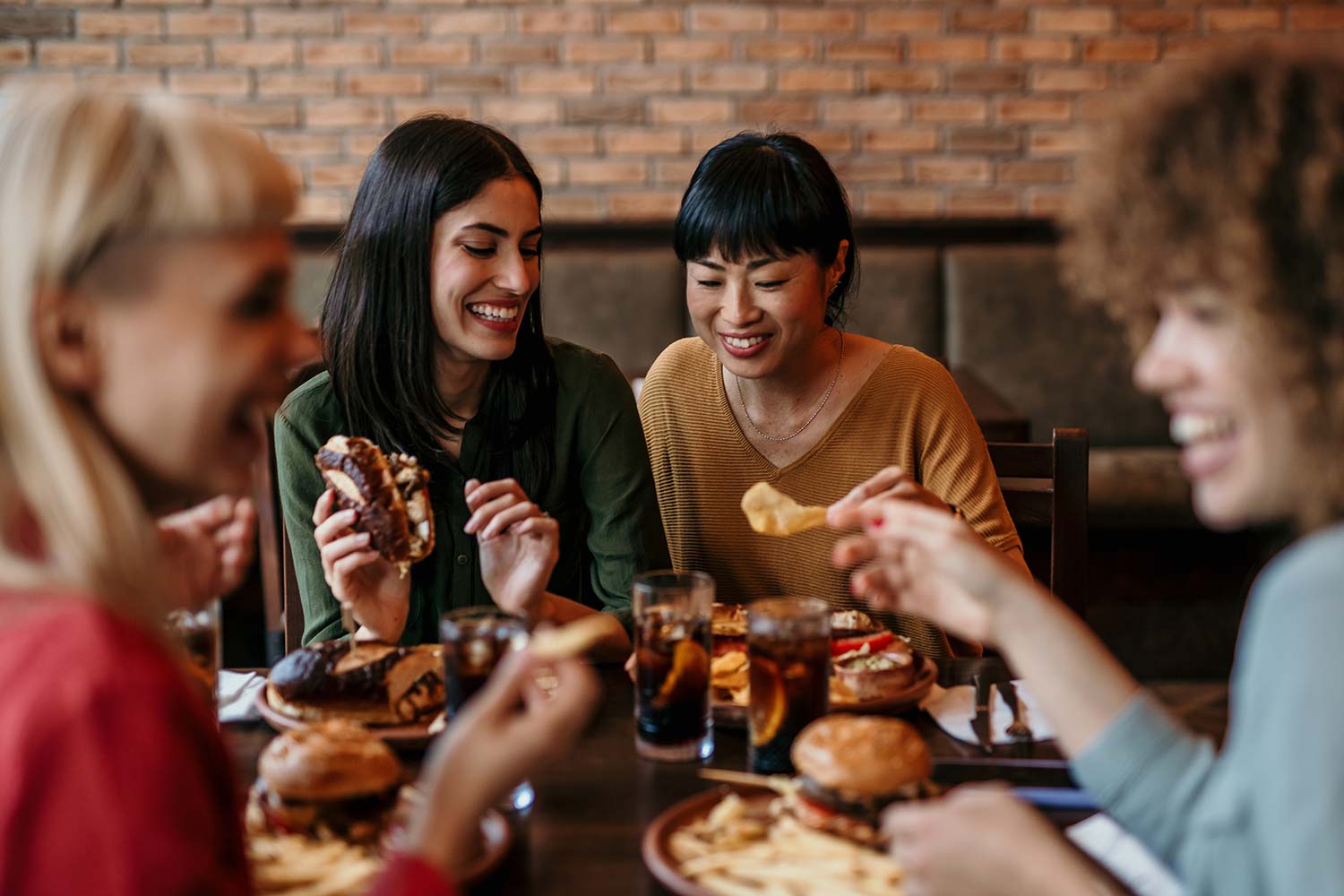 Four friends at a restaurant eating burgers