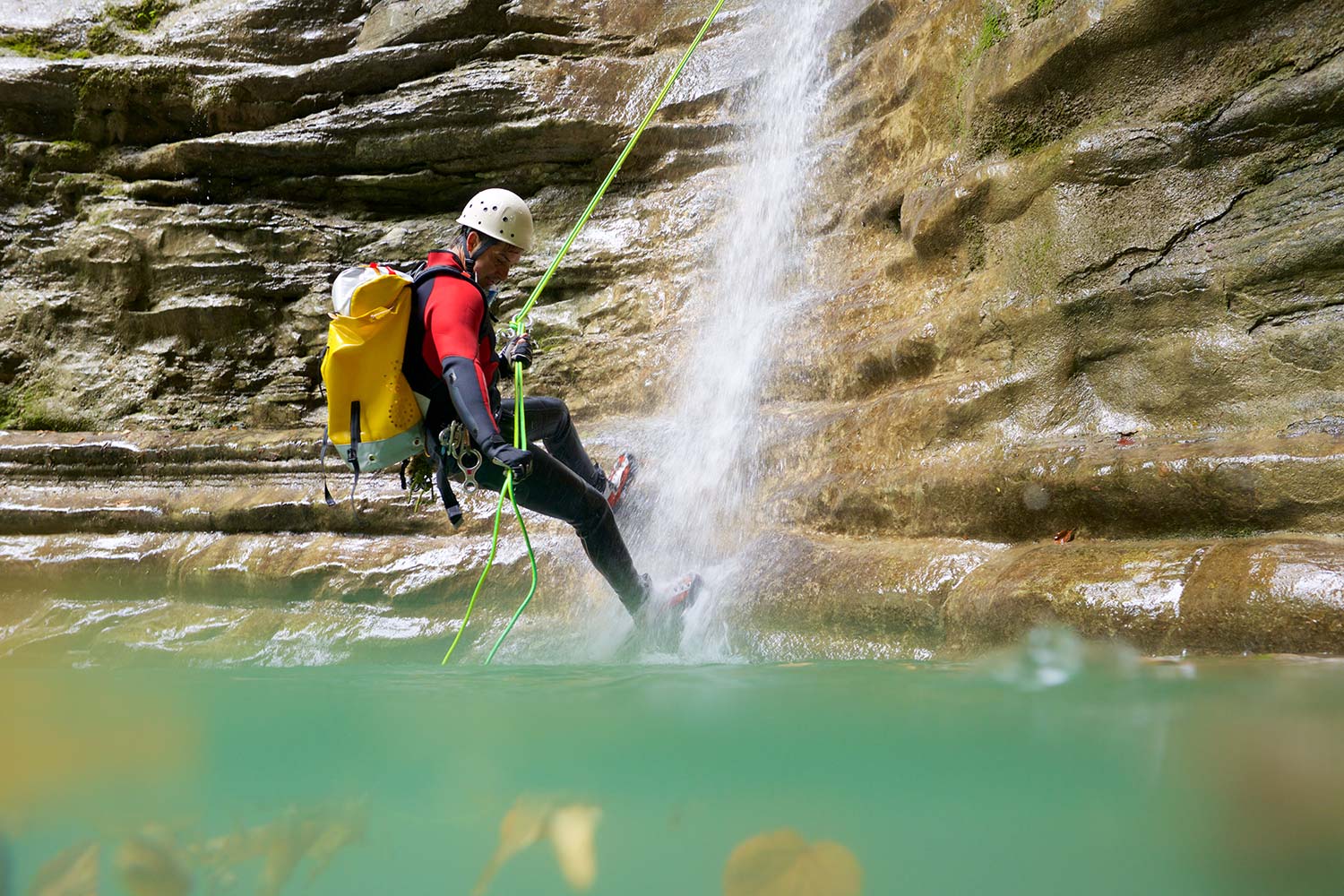 Man rappeling beside a waterfall